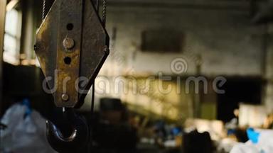 仓库里有起重机。 库存录像。 工业废弃仓库背景上悬挂的旧生锈起重机吊钩
